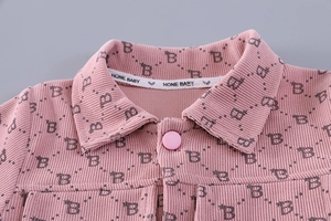 Detail of pink corduroy toddler jacket featuring letter B pattern and branded collar