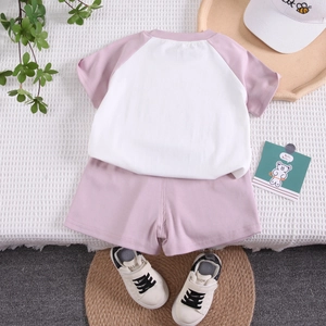 Ensemble d'été en coton rose et blanc avec t-shirt et short posé à plat sur fond blanc