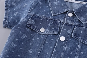 Détail de chemise en jean fille avec imprimé nœuds cœurs, coutures col et boutons argent