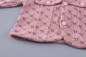 Detail of pink corduroy fabric with B-letter monogram print and matching snap buttons