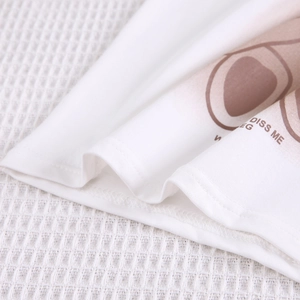 Détail de la maille en coton blanc avec imprimé marron et couture d'ourlet soignée