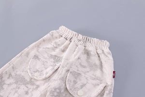 Detail of off-white corduroy baby pants featuring marble print and elastic waistband