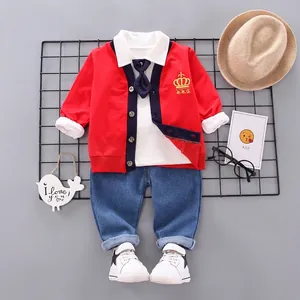 Detail of boys' British style red cardigan with gold crown embroidery and casual shirt