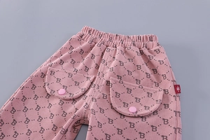 Detail of pink corduroy kids' trousers featuring B-letter print and flap pockets