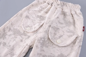 Detail of baby corduroy pants with elastic waist and size 80 label in cream marble