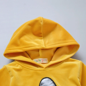 Close-up of golden velvet hoodie featuring a soft texture, brand label, and graphic print