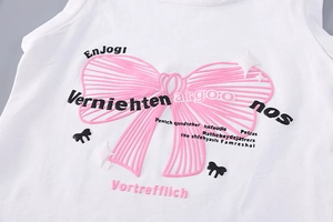 Détail de l'imprimé nœud rose et lettrage en relief sur haut blanc pour enfant