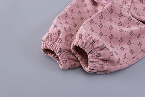 Detail of pink corduroy fabric with letter B print and elastic cuff on toddler jacket