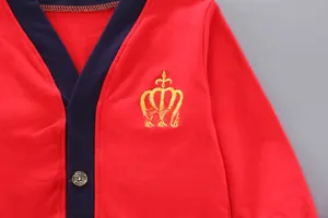 Detail of red kids' hooded knit cardigan featuring crown embroidery and branded buttons