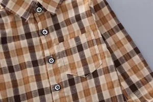 Detail of long-sleeved plaid shirt with chest pocket and classic brown checkered pattern