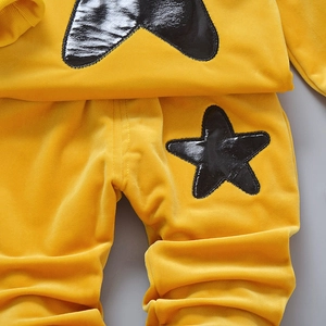Detail of yellow velvet kids tracksuit featuring black star pattern and soft texture