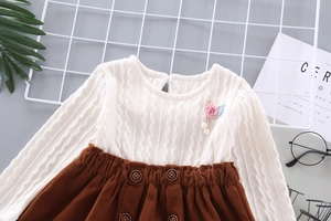 Detail of cable knit texture on baby girl dress with 3D flower and pearl pendant