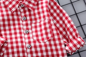 Dettaglio camicia a quadri bianchi e rossi per bambini con taschino e bottoni neri