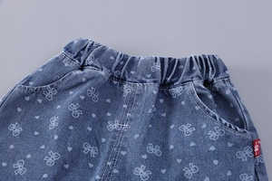 Détail de la taille élastique du short en jean bleu avec motifs nœuds et cœurs blancs