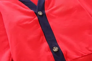Detail view of red children's knit cardigan with crown embroidery and contrast collar