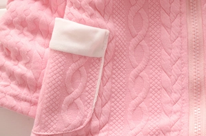 Détail du tissu en maille rose pour fille avec motifs torsadés et poche zippée