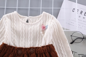 Detail of knit sweater with floral applique and corduroy skirt for toddler girls