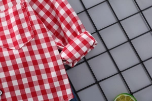 Dettaglio di camicia a quadretti rossi e bianchi in cotone con polsini e taschino