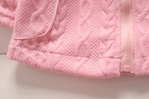 Détail de la maille torsadée rose et de la fermeture éclair du pull pour fille