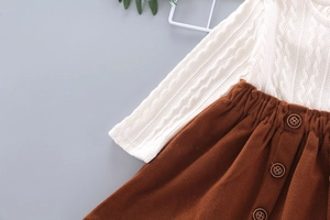 Detailed texture of cable knit sweater and brown corduroy skirt with vintage buttons