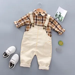 Detailed flat lay of children's plaid shirt and beige suspender pants set