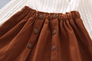 Detailed shot of knitted top and brown skirt with elastic waist and classic buttons