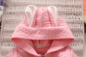 Détail du sweat à capuche rose tricoté pour enfant avec oreilles de lapin 3D et texture matelassée