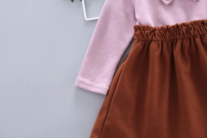 Close-up of girls' purple knit sweater sleeve and caramel brown elastic waist skirt detail