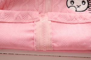 Détail d'une veste en tricot rose pour fille avec torsades et broderie animale