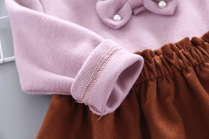 Detail of pink knitted top with bow pearl collar and brown elastic waist skirt