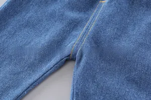 Detailed close-up of dark blue denim kids pants with reinforced orange double stitching