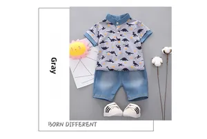 Flat lay of boys summer polo set with dinosaur print top and denim shorts with shoes