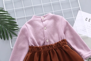 Detail of pink knitted sweater collar with pearl buttons and caramel pleated skirt