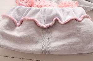 Détail du tricot gris avec dentelle à franges roses et coutures intérieures soignées