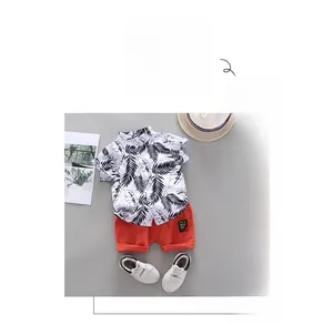 Detail of boys' short sleeve set featuring a leaf print shirt and vibrant orange shorts