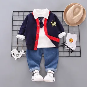 Flat lay of boy's 4-piece set including navy cardigan, white polo, and denim pants