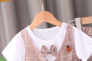 Détail d'un t-shirt blanc avec gilet à carreaux marron et nœud papillon pour garçons