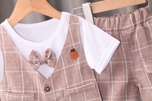 Détail du gilet à carreaux avec nœud papillon et patch cuir sur costume pour garçon