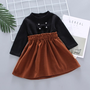 Close-up of girl's knit top with pearl bow detail and caramel pleated skirt texture