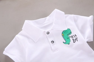 Detailansicht des Baumwoll-Poloshirts mit Dinosaurier-Print und weißen Knöpfen