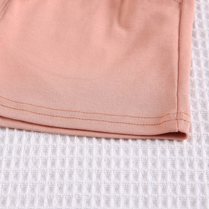 Détail du tissu en maille rose montrant l'ourlet à double aiguille et la texture douce