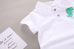 Nahaufnahme des weißen Poloshirts aus Baumwolle mit grünem Dinosaurier und Kragen
