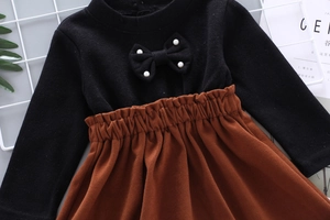 Flat lay of knit sweater with pearl bow detail and elastic brown corduroy skirt