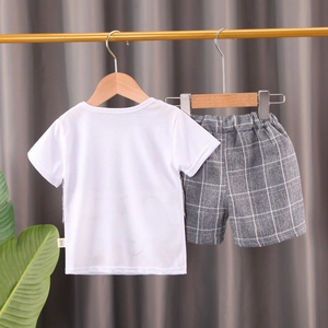 Détail d'un ensemble en coton pour bébé garçon avec t-shirt blanc et short à carreaux gris