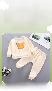 Detailed close-up of cream cotton sweatshirt set featuring orange bear print and ribbed cuffs