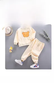 Detailed flat lay of beige toddler bear sweatshirt set with matching joggers and decor
