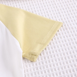 Détail des coutures doubles sur la manche raglan jaune de cet ensemble pour enfant