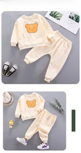 Flat lay of cream toddler tracksuit with cute cartoon bear print on cotton sweatshirt