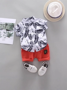 Boys summer outfit with palm leaf print shirt and orange casual shorts flat-lay display