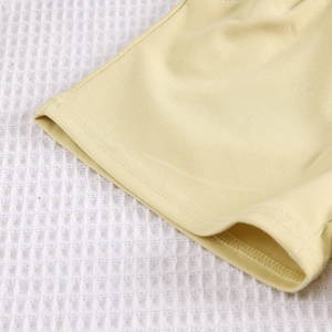 Détail de couture à double aiguille sur maille de coton jaune clair pour enfants